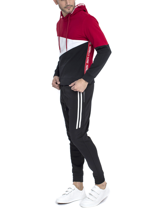 Model wearing red white and black hoodie with black jogger pants.