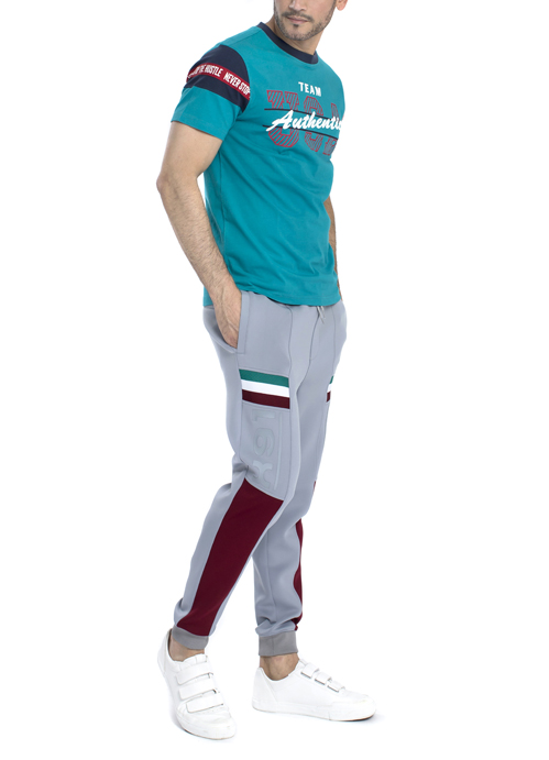 Model wearing teal shirt with grey jogger pants.