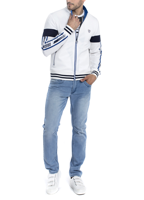 Model wearing long sleeve white jacket with blue jeans.