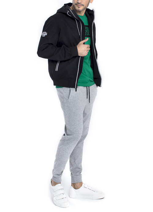 Model wearing black jacket and green design shirt with grey jogger pants.