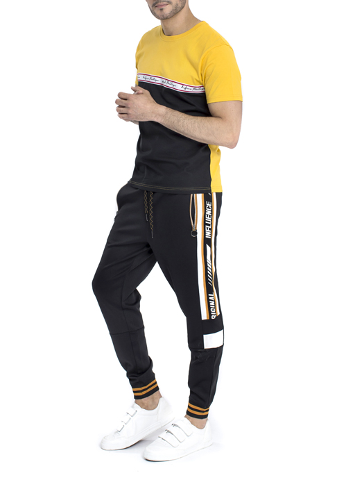 Model wearing yellow and black shirt with black jogger pants.